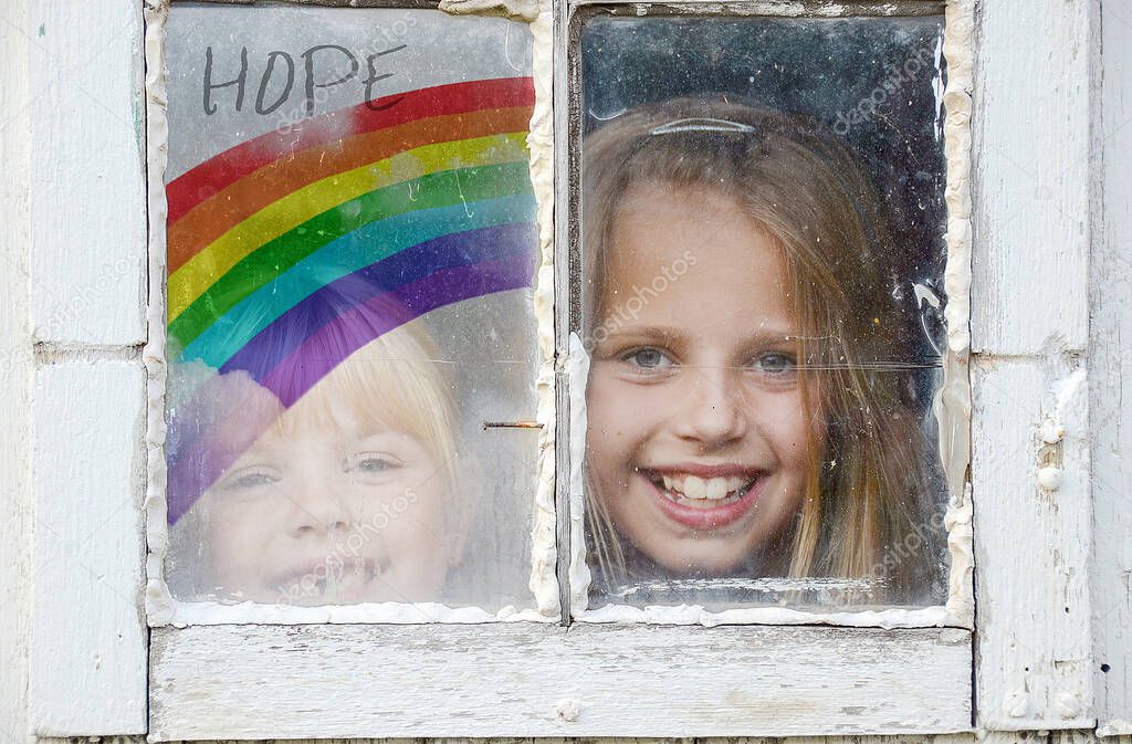 two young girls in grungy window with rainbow sign of hope