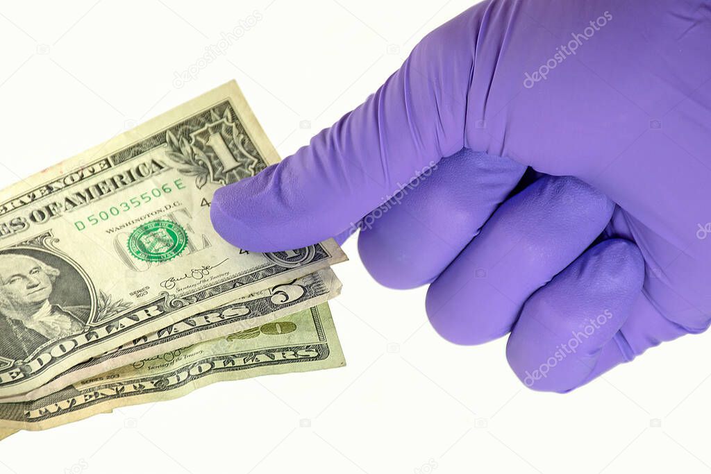 purple latex glove protecting hand from germs on dollar bills