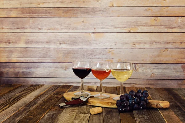 Wine flight on cutting board with grapes, cork and bottle opener — Stock Photo, Image