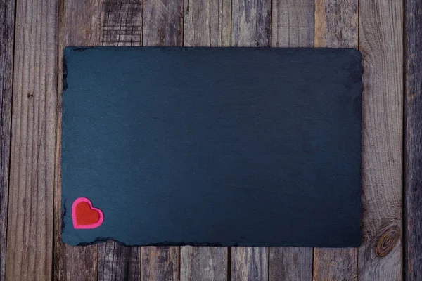 Tablero de piedra pizarra con corazón sobre fondo de madera —  Fotos de Stock