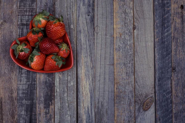 Hjärtformad skål med jordgubbar på trä bakgrund — Stockfoto