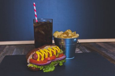 Cips ve içki koyu arka plan üzerinde gurme sosisli.