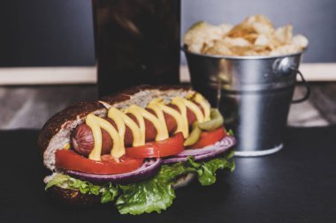 Cips ve içki koyu arka plan üzerinde gurme sosisli.