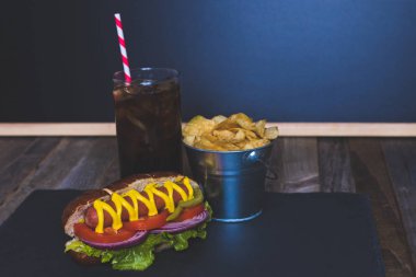 Cips ve içki koyu arka plan üzerinde gurme sosisli.