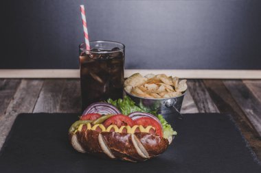 Cips ve içki koyu arka plan üzerinde gurme sosisli.