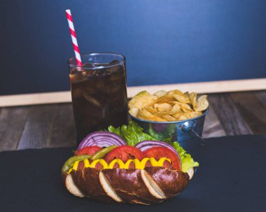 Cips ve içki koyu arka plan üzerinde gurme sosisli.