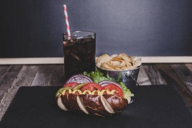 Cips ve içki koyu arka plan üzerinde gurme sosisli.