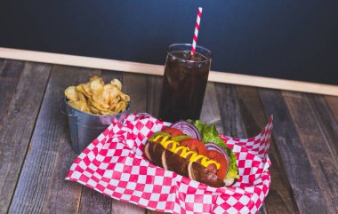 Cips ve içecek şemsiye ile sepet içinde gurme sosisli na