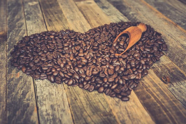 Kahve çekirdekleri ahşap arka plan üzerinde kalp şeklinde — Stok fotoğraf