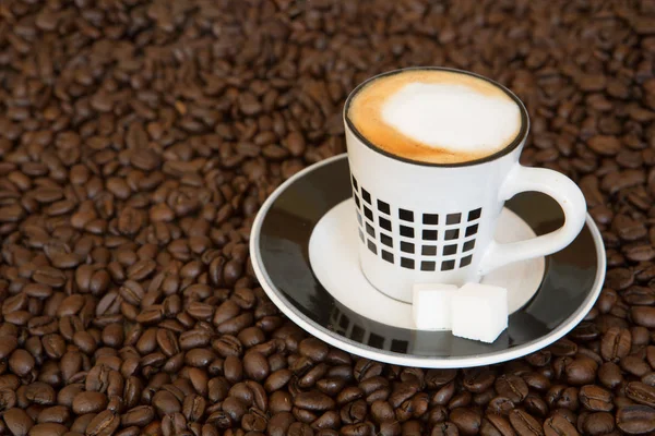 Singola piccola tazza di caffè su sfondo chicchi di caffè Immagine Stock