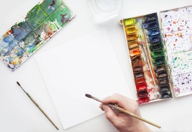 Sanatçı gibi davran. Fırça elinin yanında fotokopi alanı olan boş beyaz sayfa. Mesaj için yer var. Uzayı kopyala Düz yatıyordu. Üst Manzara. Sanatçı gibi davran. Mutlu ressam. Yaratıcı hayal gücü kavramı.