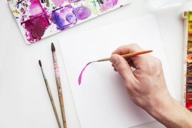 Art Flat yatıyordu. Beyaz arka planda, palet ve fırçaların yanına pembe boyalı bir çizgi çiz. Mesaj için yer var. Uzayı kopyala Üst Manzara. Palet, ofis, hobi yaşam tarzı.