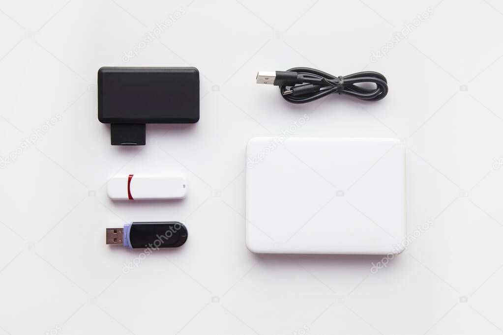 Technological  Flat lay. Computer memory accessories on the white background. Top view on the flash card, flash drive, card reader, external drive and usb cabel on the desk. Copy Space for text.
