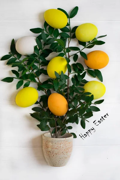 Easter tree with multi-colored Easter eggs on a white background with green spring branches