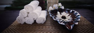 Beyaz havlu ve bir kap su ve bir çiçek yığını.