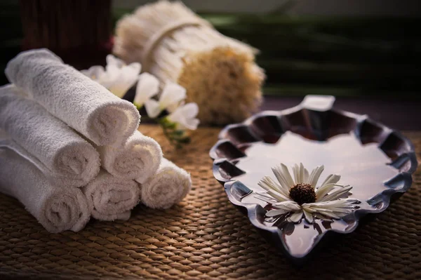 Een stapel witte handdoeken en een container van het water en een bloem. — Stockfoto