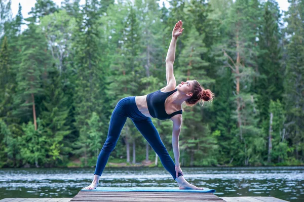 Yogi Mädchen praktiziert Yoga, macht utthita trikonasana Übungen, e — Stockfoto