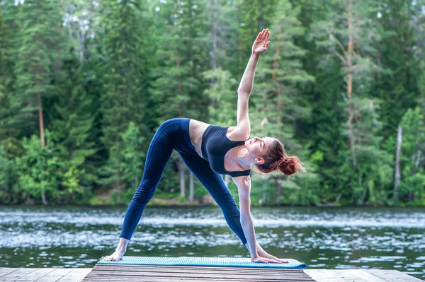 Yogi-Mädchen praktiziert Yoga, macht utthita trikonasana-Übungen — Stockfoto
