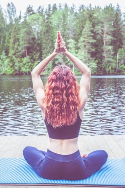 Genç bir kız gölde yoga yapıyor. Kadın mutluluğu. Sağlıklı yaşam ve doğal denge kavramı 