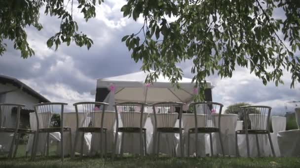 Cadeiras de casamento sob as árvores com clima nublado Videoclipe