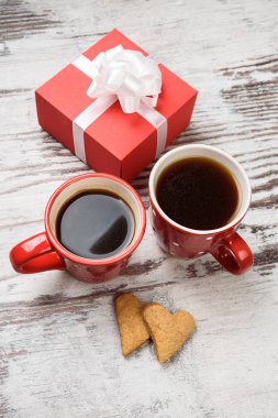 Kırmızı kahve fincanı, kalp cokies ve hediye kutusu.