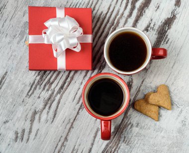 Kırmızı kahve fincanı, kalp cokies ve hediye kutusu.