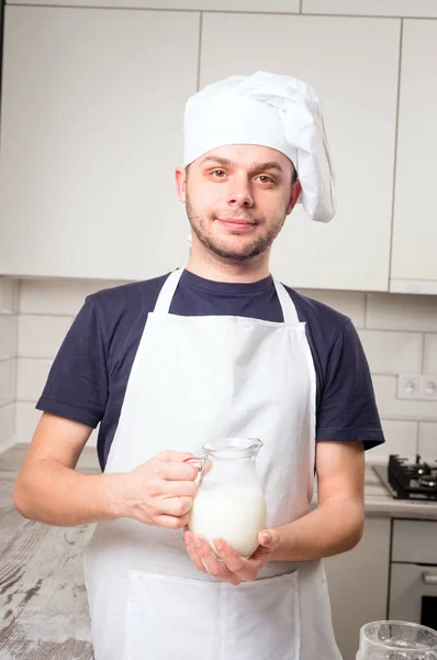 Chef cook pours milk in a glass — Stock Photo, Image