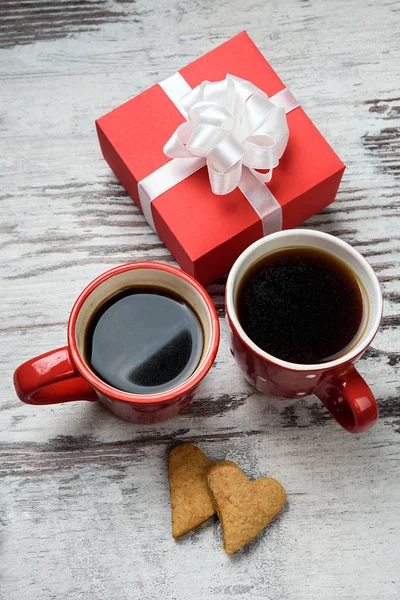 Kırmızı kahve fincanı, kalp cokies ve hediye kutusu.