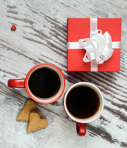 Kırmızı kahve fincanı, kalp cokies ve hediye kutusu.