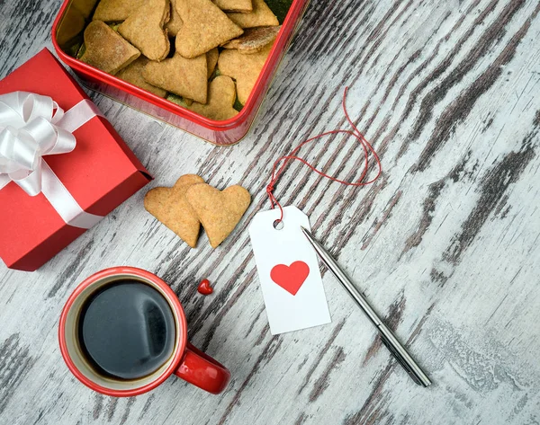Kırmızı kahve fincanı, kalp cokies ve hediye kutusu.