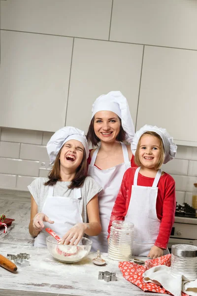 Madre con las niñas preparan la masa para hornear —  Fotos de Stock