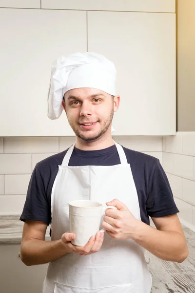 Baker hold a cup and — Stock Photo, Image