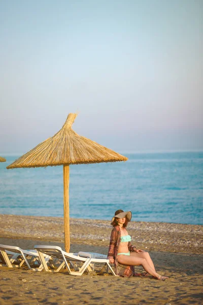 Menina em uma praia, sob um guarda-chuva de praia — Fotografia de Stock
