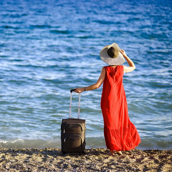 Mulher em vestido vermelho com mala mar — Fotografia de Stock