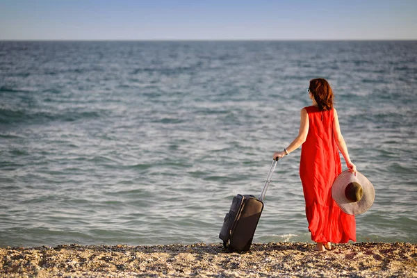Mulher em vestido vermelho com mala mar — Fotografia de Stock