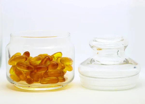 Kabeljauleberöl Omega-3-Gel-Vitamin-E-Kapseln isoliert auf weißem Hintergrund in einer transparenten Glasflasche mit Glasdeckel — Stockfoto