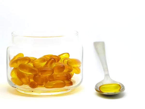 Kabeljaulebertran Omega-3-Vitamin-E-Gel-Kapseln isoliert auf weißem Hintergrund in einer transparenten Glasflasche mit einem Stahllöffel — Stockfoto