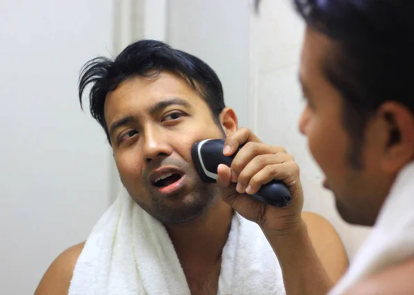 Man looking after his appearance in front of a mirror beauty styling lifestyleman lookingIndian asian after his appearance in front of a mirror beauty styling lifestyle. Shaving routine — Stock Photo, Image