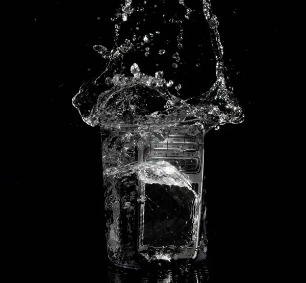 Viejo teléfono vintage salpicado en vaso de agua en fondo negro — Foto de Stock