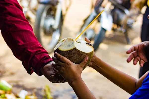 A szalma kókusz kókusz víz átadni egy kölyök eladó. természetes trópusi italt. — Stock Fotó