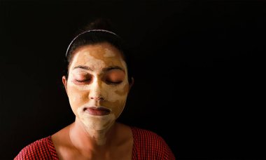 Yüz maskesi yarı kurumuş, gözleri kapalı, Hintli bir kadın.