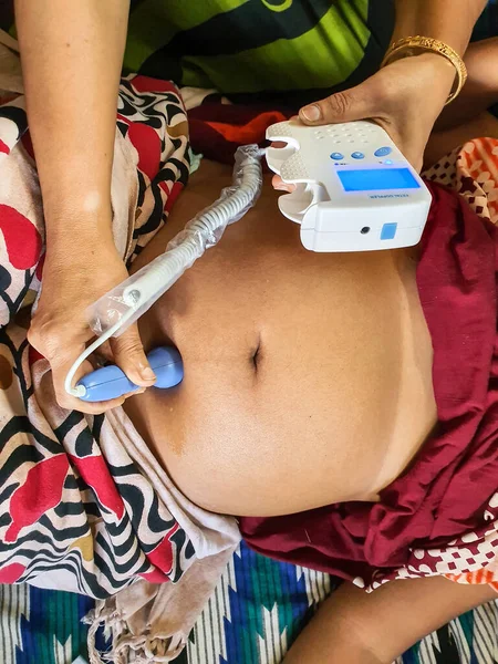 Escuchar el sonido del corazón fetal en el vientre de una mujer embarazada por una máquina doppler fetal por una trabajadora de la salud entrenada en el hogar indio — Foto de Stock