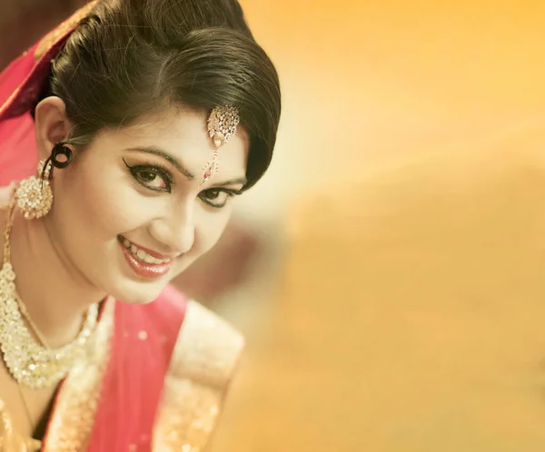 Impressionante noiva indiana vestida com roupas de casamento tradicionais vermelhas hindus sari bordado com jóias de ouro e um véu sorrisos concurso com espaço extra cópia . — Fotografia de Stock