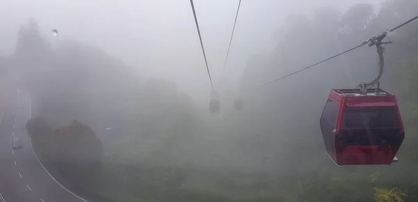 Teleférico en las tierras altas de genting, Malasia en un tiempo nebuloso con hierba verde visible desde el interior teleférico — Foto de Stock