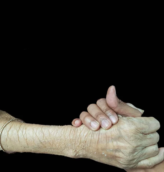 Mano di un anziano che tiene la mano di un giovane, concetto di sostegno anziano in background nero — Foto Stock