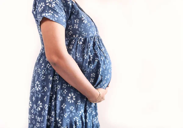 A pregnant lady with blue dress and hands on belly. — Stock Photo, Image