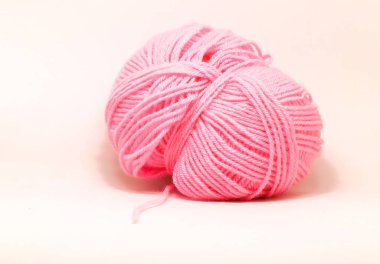 Beyaz arkaplanda pembe yün bir top.