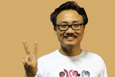 Gülümseyen ve kendinden emin bir manipuri Kuzeydoğu Hindistanlı gözlüklü adam iki parmağıyla zafer işareti gösteriyor.