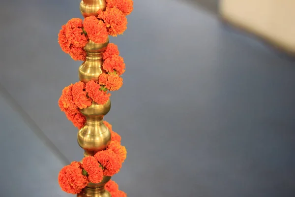 Chaine de fleurs de souci enroulée autour de la base de support de lampe en laiton . — Photo