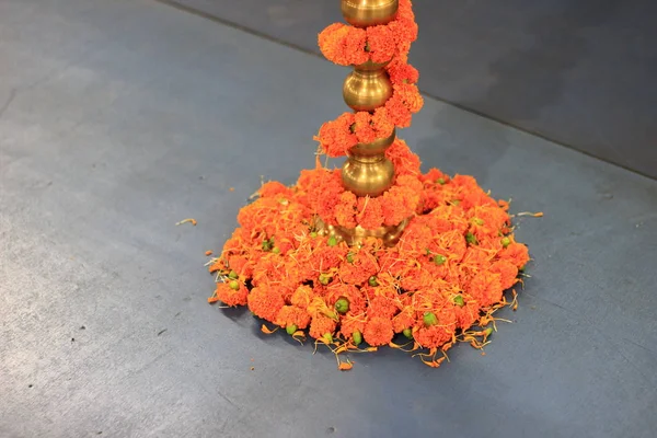 Chaine de fleurs de souci enroulée autour de la base de support de lampe en laiton . — Photo